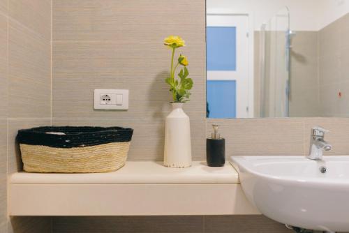 uma casa de banho com um lavatório e um vaso com uma flor em Janare - Rooms & Terrace em Nápoles