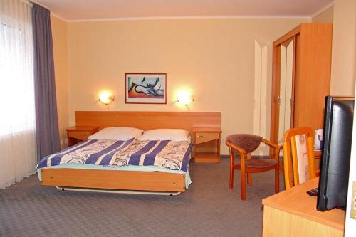 a bedroom with a bed and a desk and a television at Hotel Europa in Jastrzębia Góra