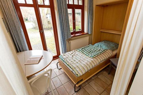 een kleine kamer met een klein bed en een tafel bij Ferienhaussiedlung Strandperlen Weidenhof 2a (Typ III) in Wustrow