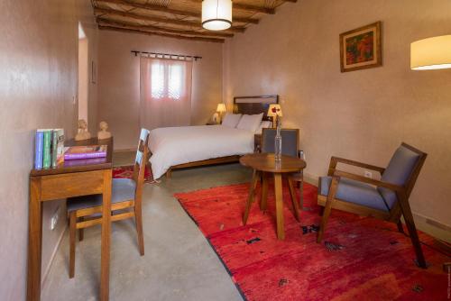 a bedroom with a bed and a desk and a table at Côté Sud in Ouarzazate