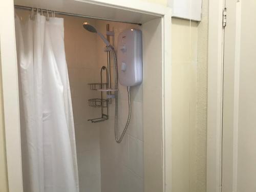 a shower in a bathroom with a white shower curtain at The Sandpiper in Barmouth