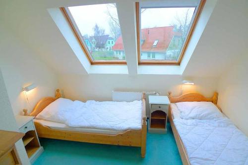 two beds in a small room with two windows at Ferienhaussiedlung Strandperlen Sanddornhof 8b (Typ IX) in Wustrow