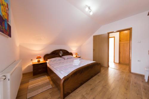 1 dormitorio con 1 cama grande y suelo de madera en Apartman Eva Maria, en Otočac