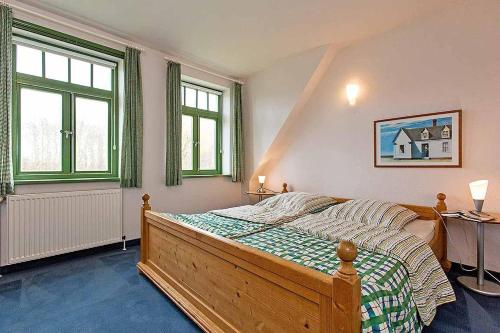 ein Schlafzimmer mit einem Bett und zwei Fenstern in der Unterkunft Ferienhaussiedlung Strandperlen Sanddornhof 3b (Typ VI) in Wustrow