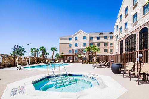 a swimming pool with chairs and a building at Staybridge Suites El Paso Airport by IHG in El Paso