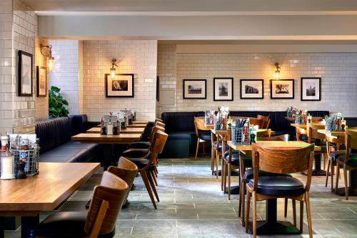 un restaurante con mesas de madera y sillas en una habitación en The George en Cheltenham