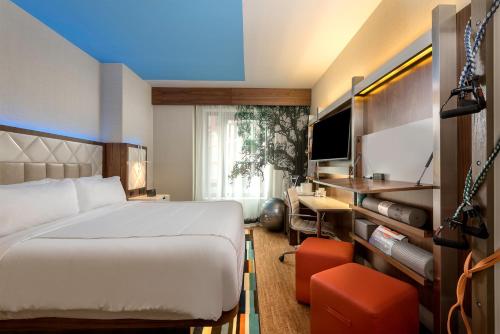 紐約的住宿－EVEN Hotel New York - Midtown East, an IHG Hotel，一间卧室配有一张床、一张书桌和一台电视
