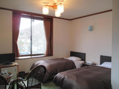 a hotel room with two beds and a window at Chuzenji Pension in Nikko