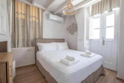 a white bedroom with a bed with towels on it at Geant Suites Mykonos in Mikonos