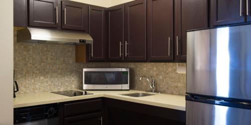 a kitchen with wooden cabinets and a stainless steel refrigerator at Staybridge Suites Fargo by IHG in Fargo