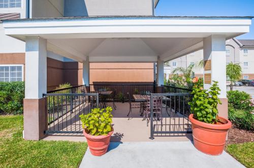a covered patio with tables and potted plants at Candlewood Suites Lake Jackson by IHG in Lake Jackson