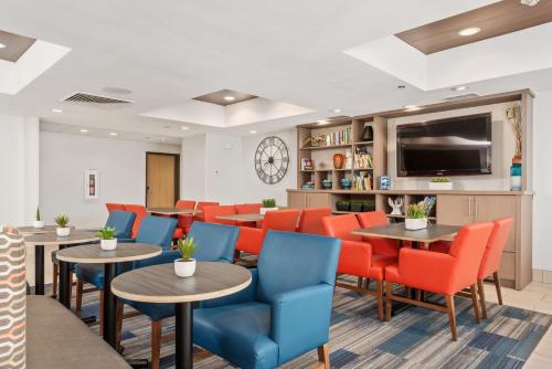 a waiting room with tables and chairs and a flat screen tv at Holiday Inn Express West Valley City by IHG in West Valley City