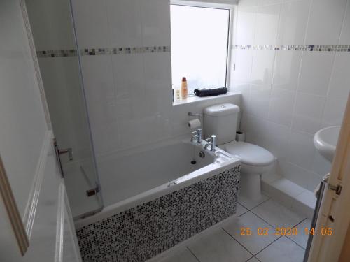 a bathroom with a tub and a toilet and a sink at Oakdene Apartments in Windermere