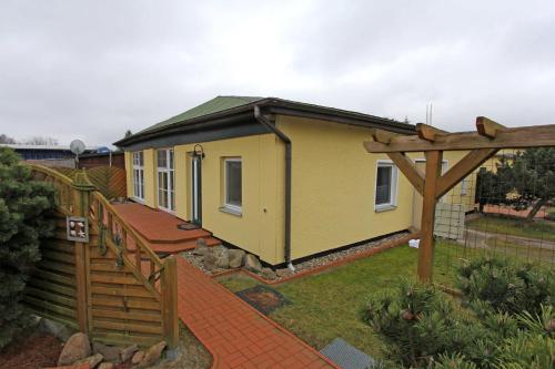 a small yellow house with a wooden fence at Ferienhaeuser Zinnowitz USE 3420 in Zinnowitz