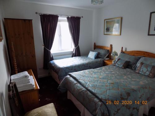 een slaapkamer met 2 bedden en een raam bij Oakdene Apartments in Windermere