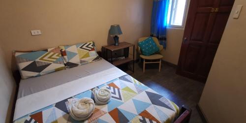 a bedroom with a bed and a chair and a window at UNK'S HOUSE HOMESTAY in Panglao