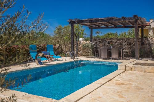 a swimming pool with two chairs and a pergola at Holiday house BRZAC in Brzac