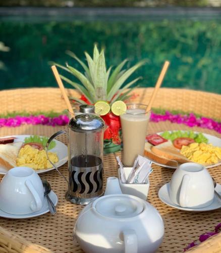 a table with plates of food and drinks on it at Kukuh House Ubud in Ubud