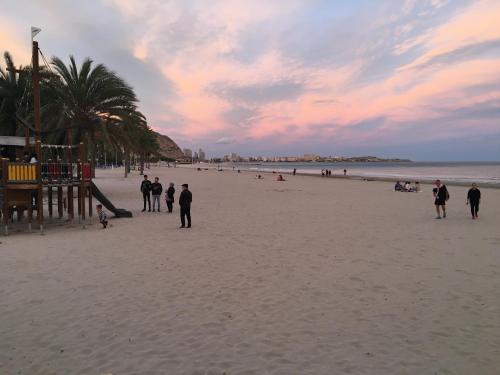 un grupo de personas caminando por la playa al atardecer en Apartamento en Alicante, Plaza de España, zona Mercado, AA, en Alicante