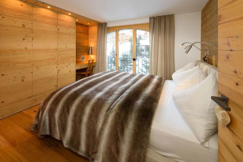 Un dormitorio con una cama con una manta. en Haus Haro en Zermatt