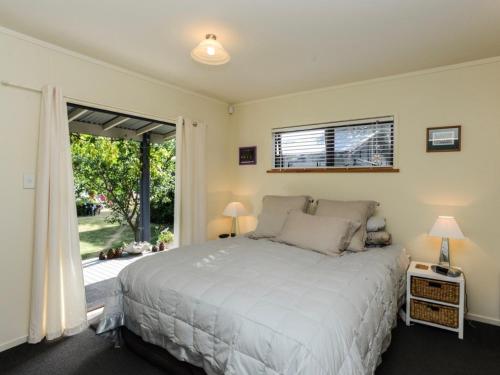a bedroom with a bed and a large window at Whamoori - Waimarama Beach Bach in Waimarama