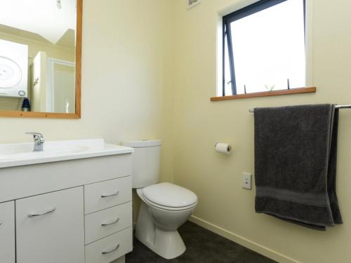 a bathroom with a toilet and a sink and a mirror at Whamoori - Waimarama Beach Bach in Waimarama