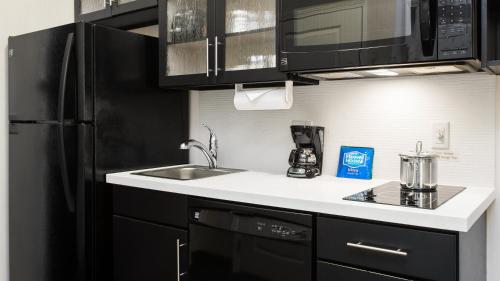 a kitchen with a sink and a black refrigerator at Candlewood Suites Grove City - Outlet Center by IHG in Grove City
