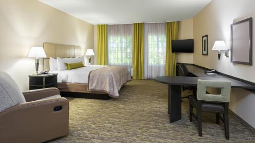 a hotel room with a bed and a desk at Candlewood Suites Grove City - Outlet Center by IHG in Grove City