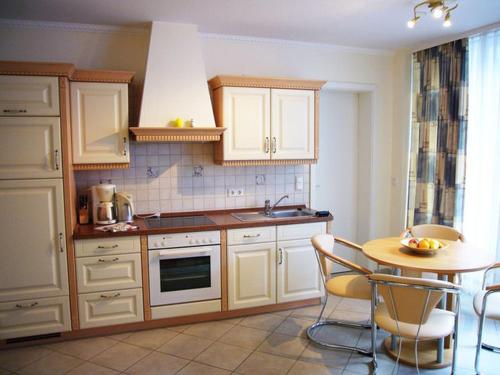 una cocina con armarios blancos y una mesa con sillas. en Villa Seestern _ Wohnung 2, en Neuhof