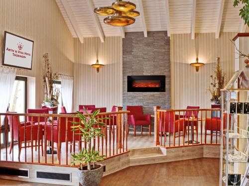 a dining room with red chairs and a fireplace at Akzent Aktiv & Vital Hotel Thüringen in Schmalkalden