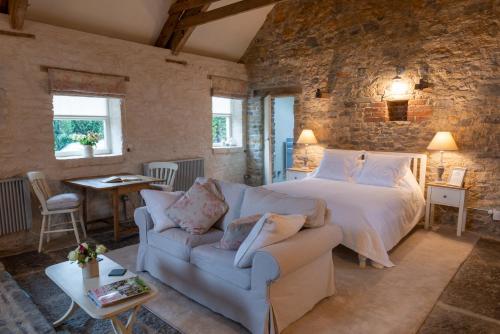 a bedroom with a bed and a couch and a table at The Barn at Amberwell in Ditcheat