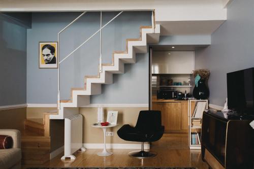 a staircase in a living room with a black chair at Casa Amora STUDIOS in Lisbon
