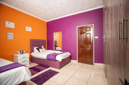 a bedroom with purple and orange walls and two beds at Sweet Holiday Homes in Victoria Falls