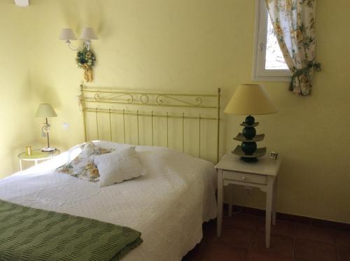 ein Schlafzimmer mit einem Bett und einer Lampe auf einem Tisch in der Unterkunft La Villa Rosalie in Ventabren