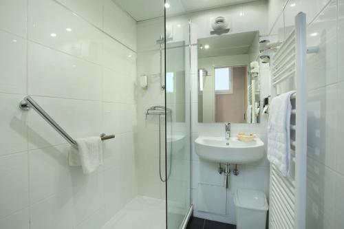 een witte badkamer met een wastafel en een douche bij Murat in Parijs