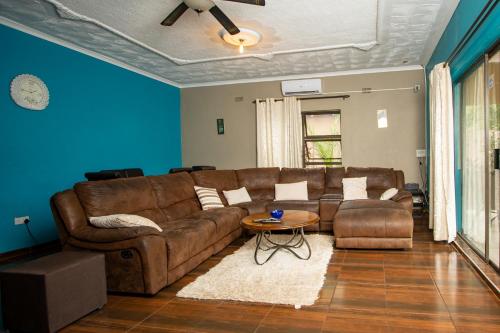 a living room with a brown couch and a table at Sweet Holiday Homes in Victoria Falls