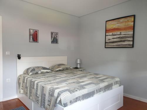 a bed in a white room with two pictures on the wall at Why Not? Guest House Espinho in Espinho