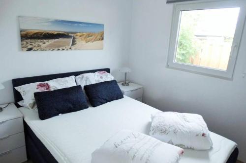 Un dormitorio con una cama blanca con almohadas y una ventana en Ferienpark Vislust Ferienhaus De Wickinger. Angler sind willkommen!, en Wervershoof