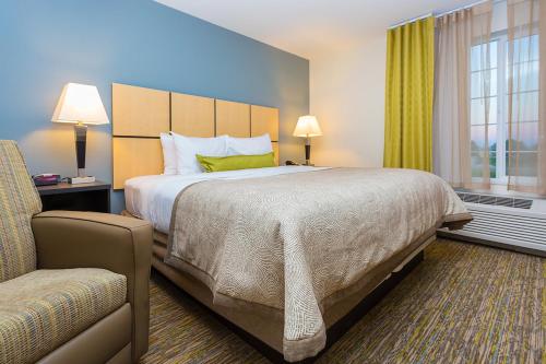 a hotel room with a large bed and a chair at Candlewood Suites Sidney by IHG in Sidney