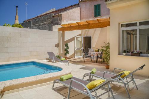 a backyard with a swimming pool and chairs and a house at Holiday Home Ribot in Ariany