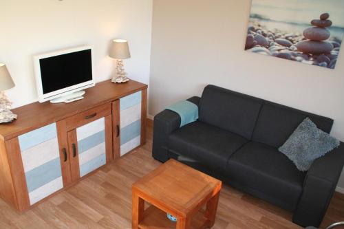 een woonkamer met een bank en een tv bij Rekerlanden 257 in Schoorldam