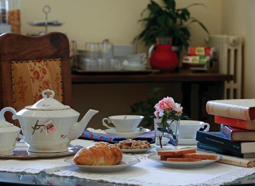 een tafel met een theepot en croissants en boeken bij B&B Luna Caprese in Napels