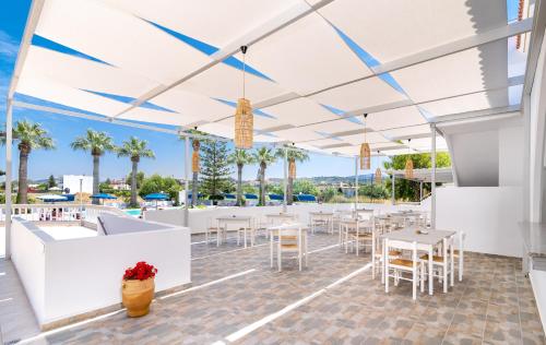 an outdoor patio with tables and chairs and palm trees at Sabina Hotel in Theologos
