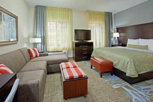 um quarto de hotel com uma cama e um sofá em Staybridge Suites Houston Stafford - Sugar Land, an IHG Hotel em Stafford