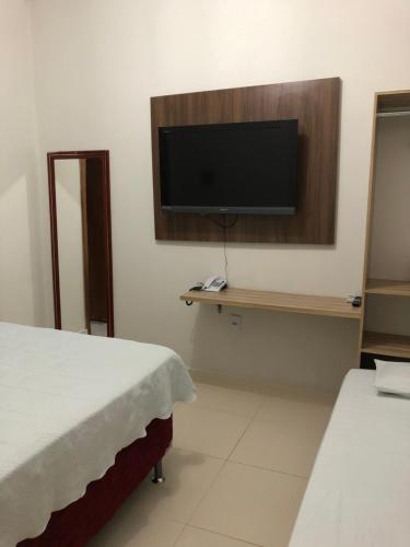 a room with two beds and a television on a wall at Kitnet Realeza in Várzea Grande
