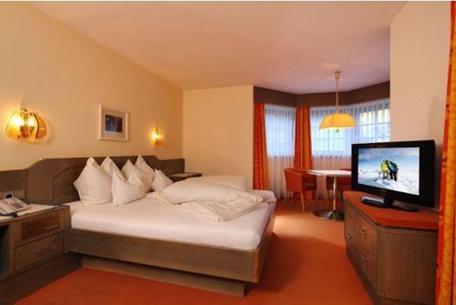 ゼルデンにあるPension Edenのベッドとテレビが備わるホテルルームです。