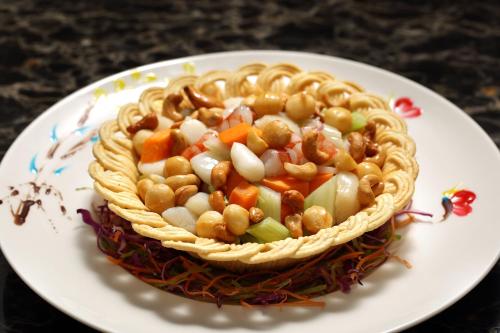 a bowl of food with nuts and vegetables on a plate at HUALUXE Yangjiang City Center in Yangjiang