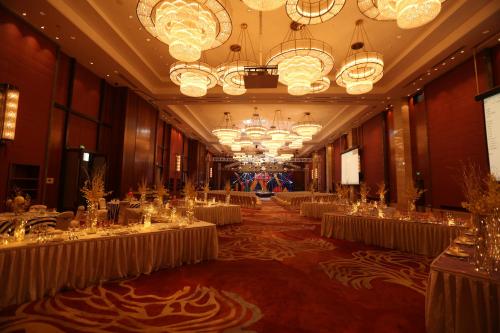 a large banquet hall with white tables and chandeliers at HUALUXE Yangjiang City Center in Yangjiang