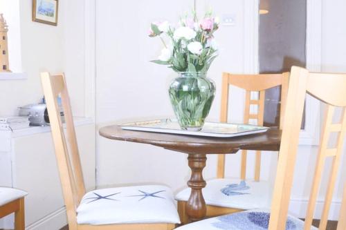 a vase of flowers sitting on a table with two chairs at Kikas Cottage, Rear 89 Church Street, White Horse Yard in Whitby
