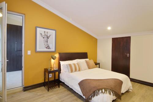 a bedroom with a bed and a yellow wall at Sandown Guest House in Johannesburg
